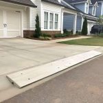 Low-profile driveway curb ramps installed in front of a double garage, designed for safe and smooth vehicle navigation over curbs.