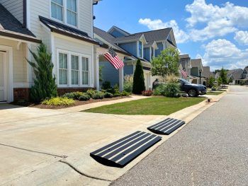 Driveway ramp with reflector installed in front of a residential home, designed to prevent car scraping and provide safe curb access.