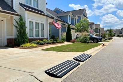 Driveway ramp with reflector installed in front of a residential home, designed to prevent car scraping and provide safe curb access.