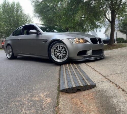Low BMW using rubber curb ramp to enter steep driveway without front lip scraping
