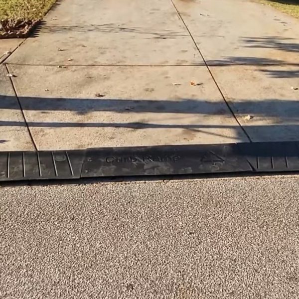 Rubber driveway curb ramp placed at the entry of a steep driveway for smooth vehicle access