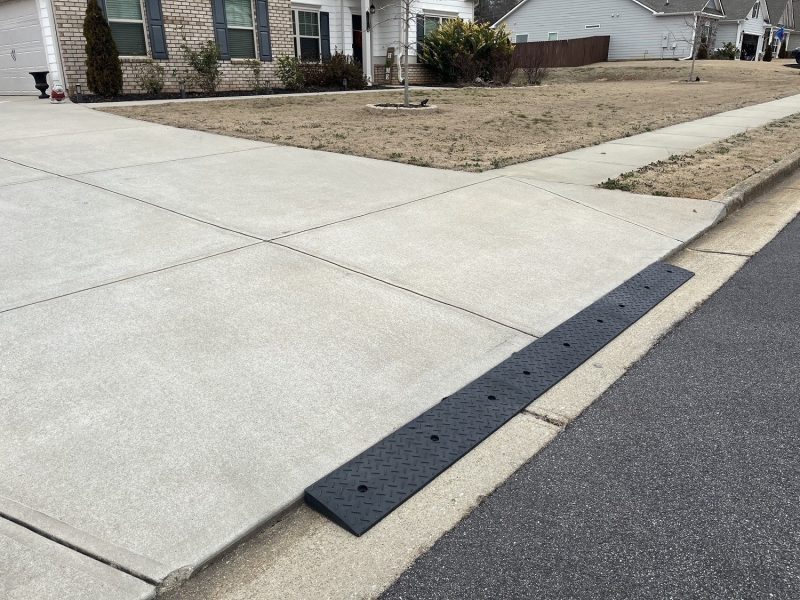 Driveway with a steep angled entry and a concrete lip fitted with a curb ramp for smooth vehicle access.