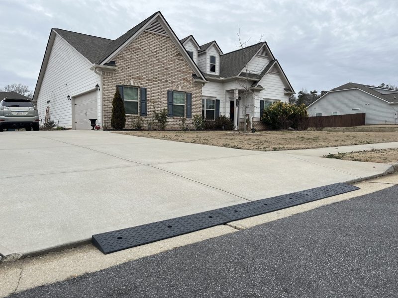 Durable curb ramp installed on a steep driveway with a lip for smooth vehicle clearance.