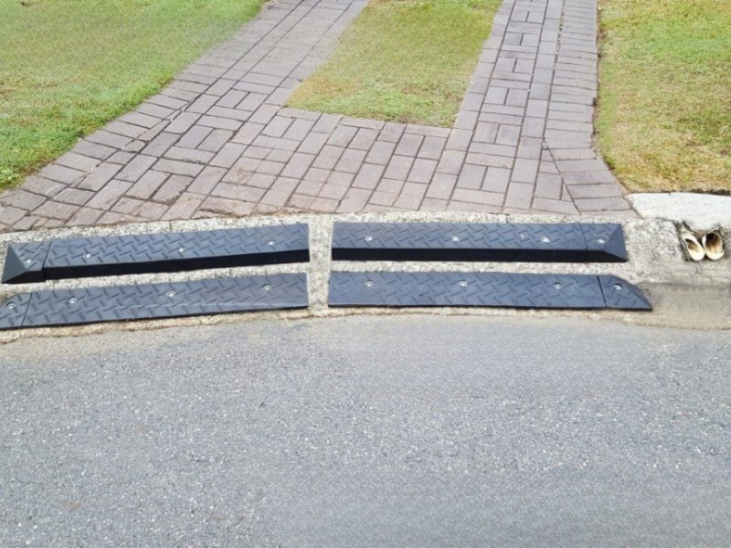 Rubber ramps installed on a mountable curb for smooth vehicle transitions and to prevent bottoming out.