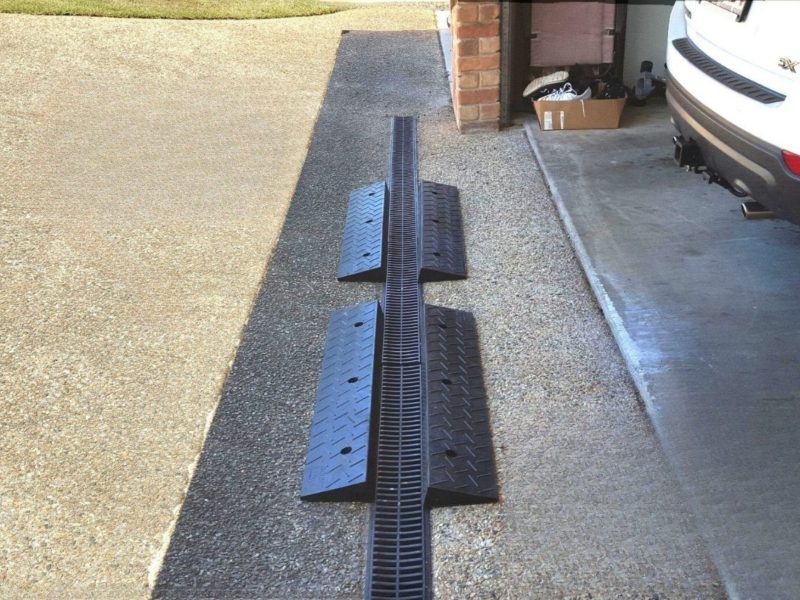 Steep driveway ramp system installed at a garage entry to provide a smooth transition for vehicles.