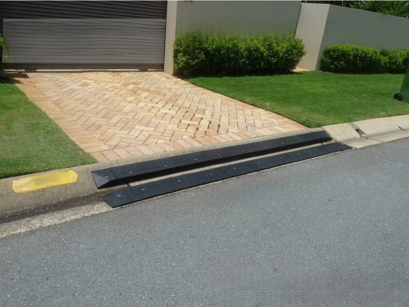 Mountable curb ramp installed on a brick driveway entry to provide smooth vehicle transitions over the curb.