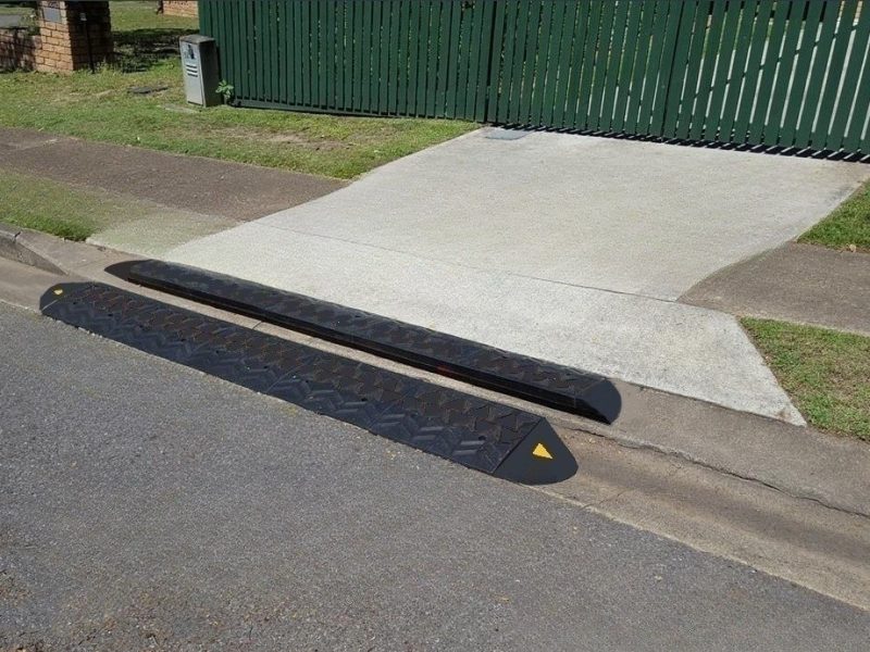 Mountable curb ramps installed at a concrete driveway with a steep incline for smooth vehicle access and scrape prevention.