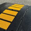 Heavy duty rubber driveway ramp closeup with textured anti slip surface and yellow traction strips