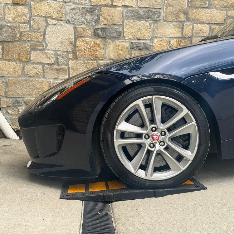 Rubber ramp over trench drain at sloped garage entry allowing low Jaguar to clear without scraping