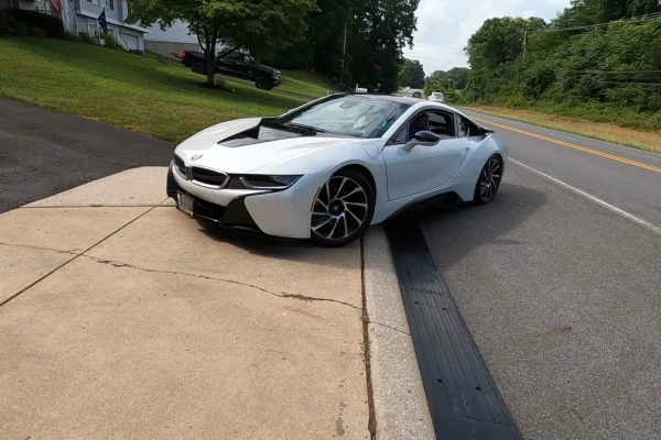 White sports car crossing a driveway curb using a black ramp to prevent scraping and ensure smooth transition.