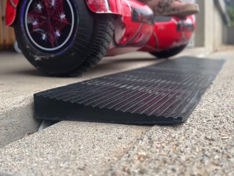 A hoverboard positioned on a ramp leading into a garage, providing smooth entry over a threshold.