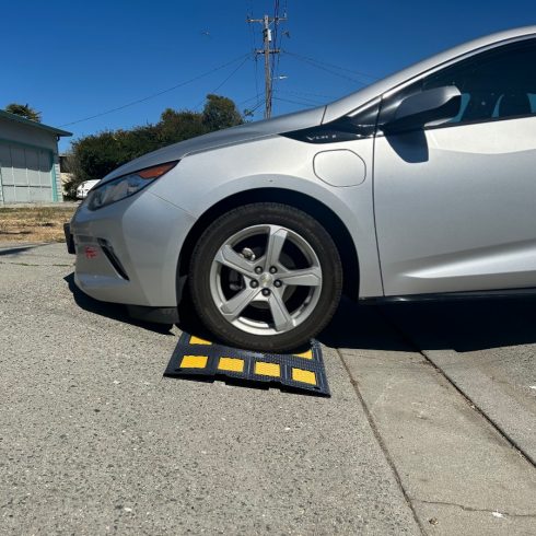 Driveway curb ramp providing clearance for a low-profile car on a steep driveway, helping prevent scraping.