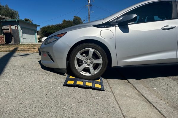 Driveway curb ramp providing clearance for a low-profile car on a steep driveway, helping prevent scraping.