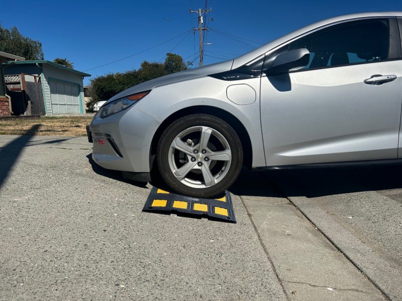 Driveway curb ramp providing clearance for a low-profile car on a steep driveway, helping prevent scraping.