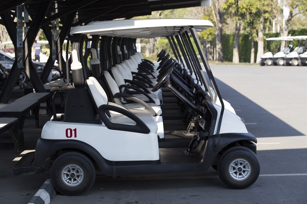 A row of golf carts parked in a cart barn, illustrating the importance of using Driveway Guardian ramps for enhanced safety and efficiency.