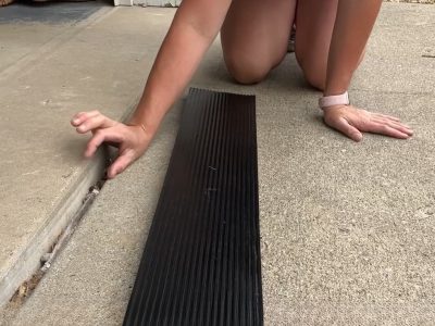 A person positioning a long rubber ramp at the threshold of a garage entryway, demonstrating easy installation.