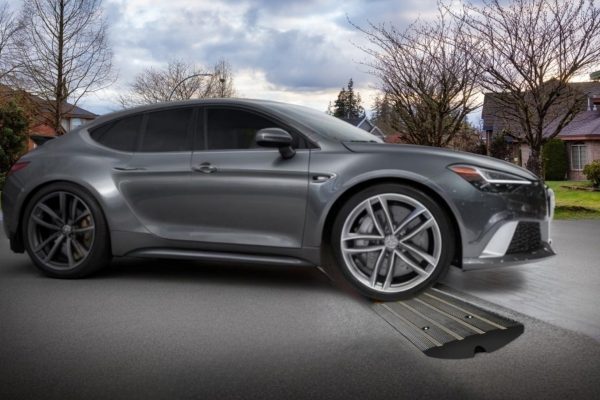 Low-profile silver car using a driveway ramp to prevent undercarriage scrapes and facilitate easy access over a steep curb.