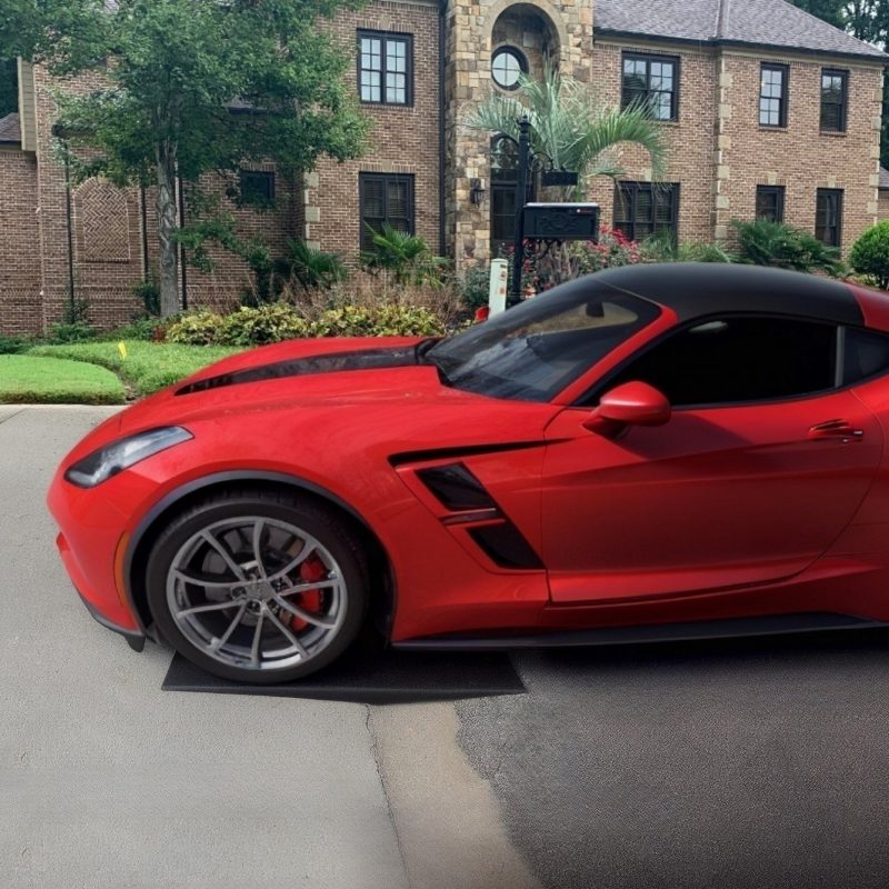 Red sports car using a Curb Ramp™ to easily access a steep driveway, preventing undercarriage scrapes and enhancing curb appeal.