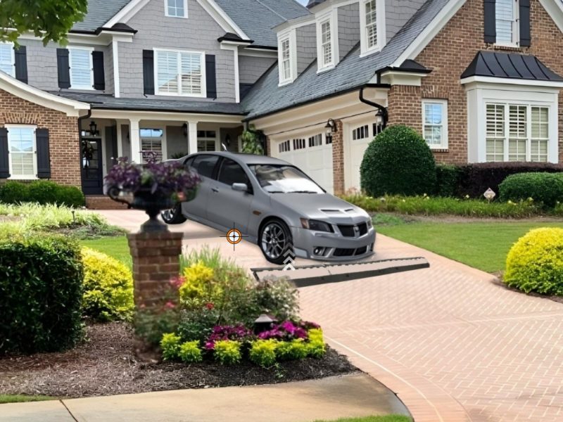 A sleek silver car using a driveway curb ramp to smoothly transition over a rolled curb in front of a modern house.