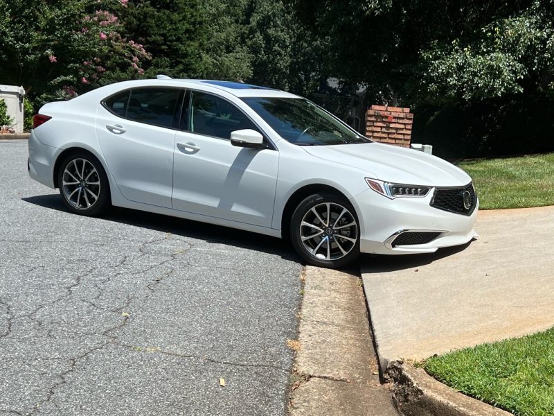 Low-clearance car scraping on a steep driveway curb while entering.