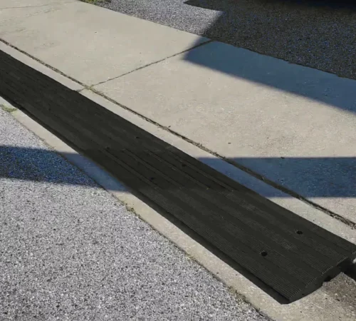 Rubber driveway curb ramp installed over a steep curb to provide a smooth transition for vehicles.