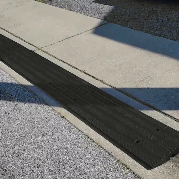 Rubber driveway curb ramp installed over a steep curb to provide a smooth transition for vehicles.