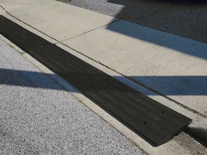 Rubber driveway curb ramp installed over a steep curb to provide a smooth transition for vehicles.