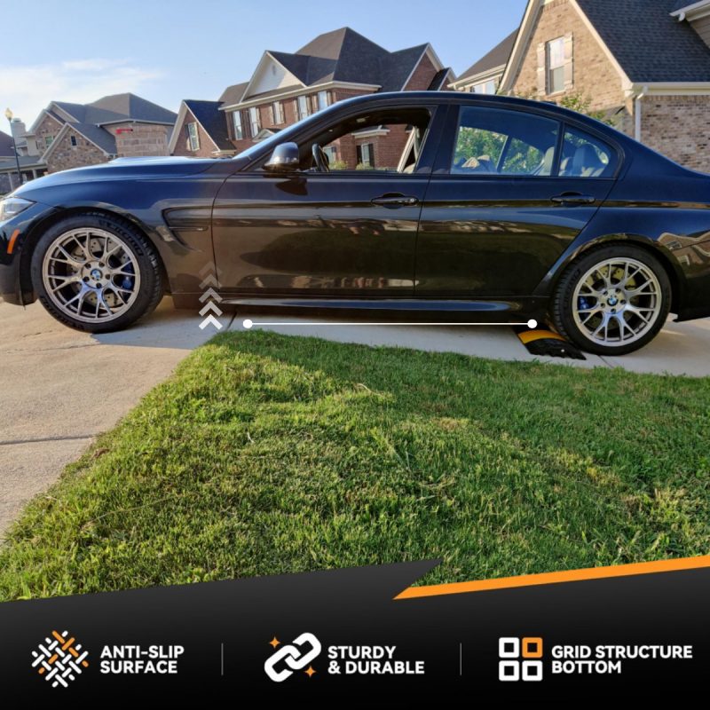 BMW sedan using a rubber ramp to prevent scraping over a steep driveway ridge.