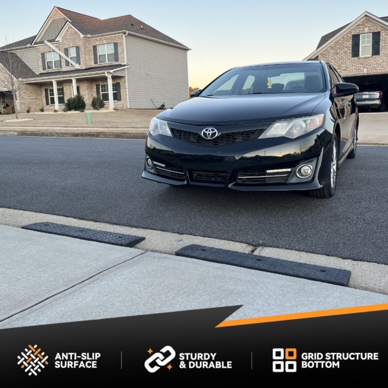 Black Toyota sedan using a driveway ramp kit to smoothly cross over a street gutter threshold.