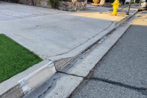 Steep Driveway Solutions – Prevent Scraping & Clearance Issues Steep driveway with a lipped curb and drainage gap, highlighting the need for a smooth driveway ramp solution.