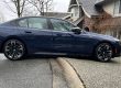 Blue BMW sedan scraping curb at steep driveway ridge, showing low clearance issue