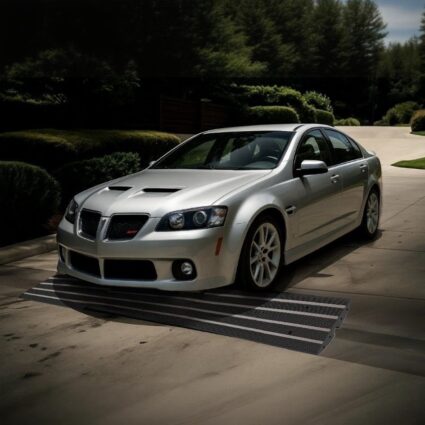 Silver sedan crossing steep driveway over wide black rubber curb ramp for smooth entry
