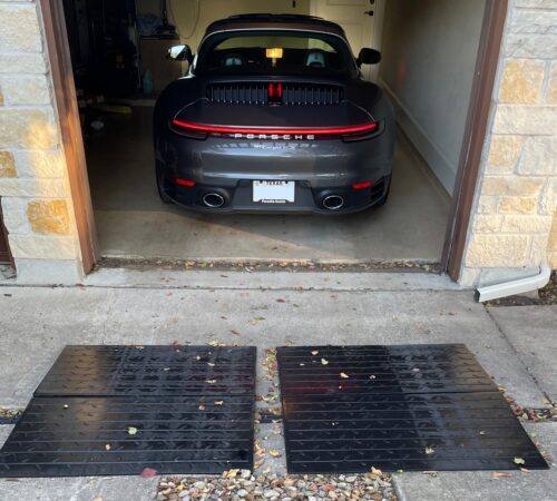 Garage Entry Ramp System for Steep Driveway Lip and Low Car Clearance Low sports car backing into a garage using large rubber entry ramps to smooth out a steep driveway lip.