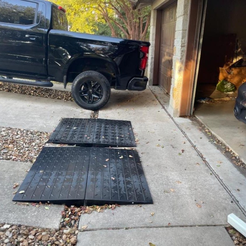 Steep Driveway-to-Garage Lip Transition Ramps for Smooth Vehicle Entry Heavy-duty rubber transition ramps placed over a steep driveway-to-garage lip to help a truck cross the threshold smoothly.