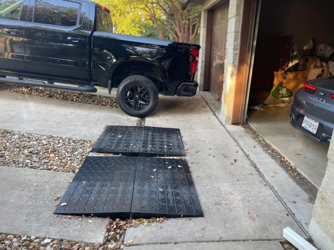 Steep Driveway to Garage Transition Ramp for Lip Clearance and Bottom-Out Prevention Heavy-duty rubber transition ramps placed over a steep driveway-to-garage lip to prevent vehicles from bottoming out.