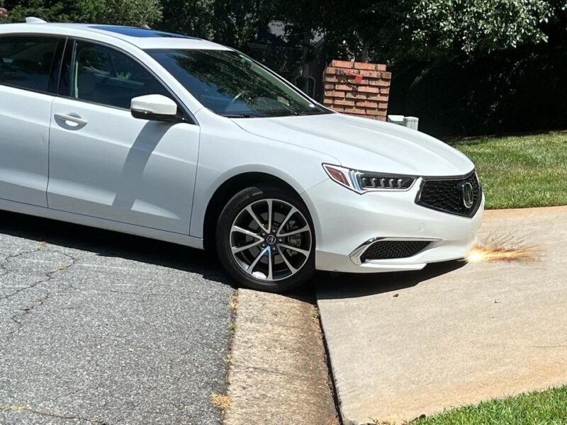 Low-clearance car front bumper scraping on a steep driveway lip during angled entry