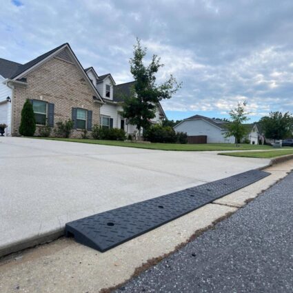 Rubber driveway curb lip ramp installed at the street edge to reduce the sharp curb drop-off that causes low cars to scrape when entering the driveway.
