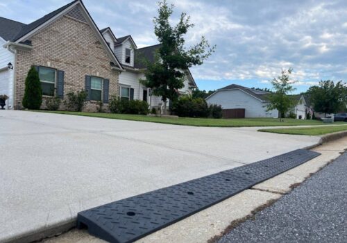 Rubber driveway curb lip ramp installed at the street edge to reduce the sharp curb drop-off that causes low cars to scrape when entering the driveway.