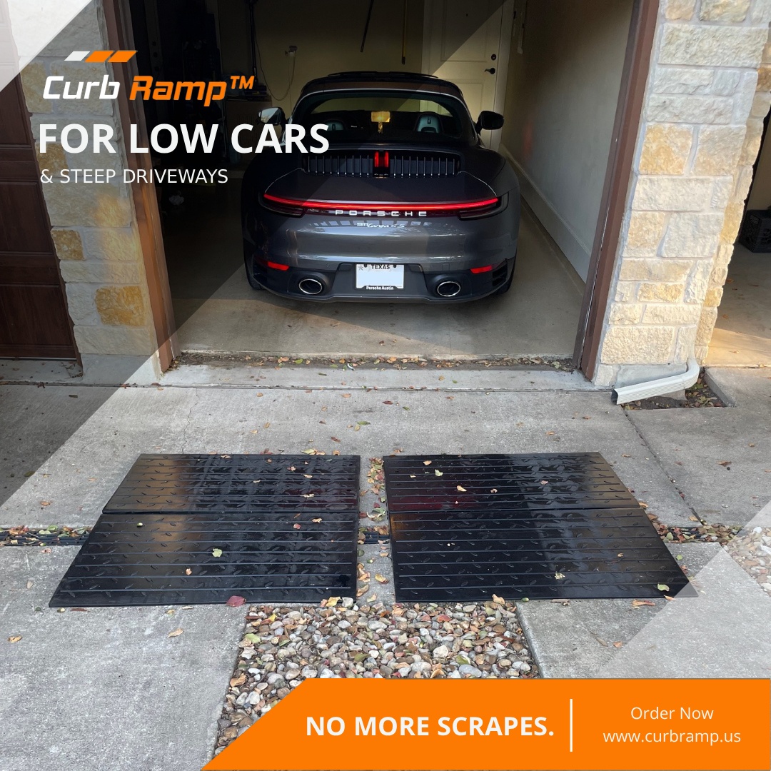 Low-clearance sports car exiting a garage with rubber driveway ramps placed to prevent rear scraping on a steep driveway drop.