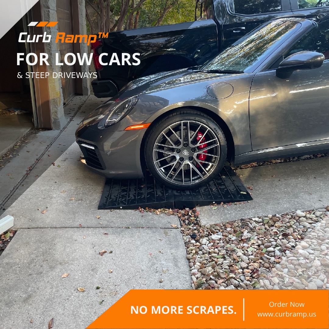Low sports car driving over rubber driveway ramps to reduce scraping caused by a steep driveway slope and sudden grade change.